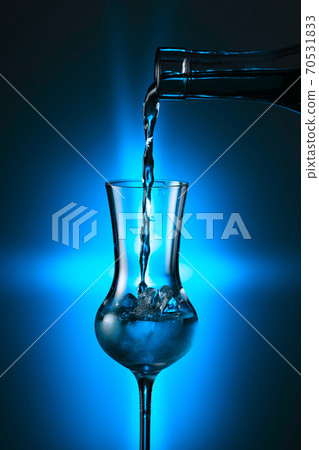 Steamed glass with strong alcoholic drink on a blue background. Steamed glass with strong alcoholic drink on a blue background. 70531833