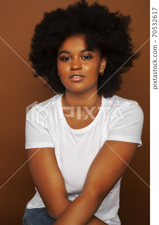 pretty young african american woman with curly hair posing cheerful gesturing on brown background, lifestyle people concept pretty young african american woman with curly hair posing cheerful gesturing on brown background, lifestyle people concept 70532617