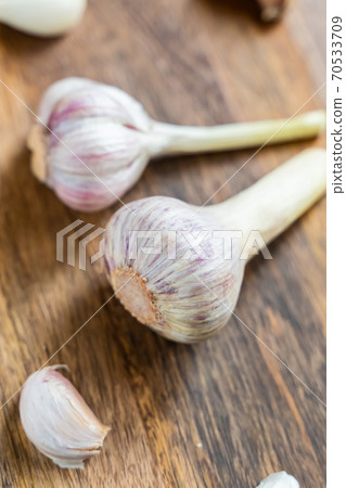 pair of garlic head in the center of scattered cloves on a wooden background pair of garlic head in the center of scattered cloves on a wooden background 70533709