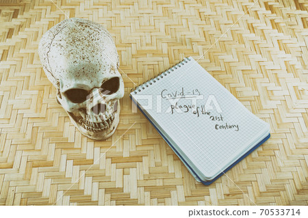human skull and notepad with the inscription covid 19 plague of the 21st century 70533714