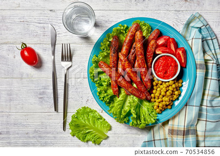 Pork sausages with tomatoes, lettuce, and peas 70534856