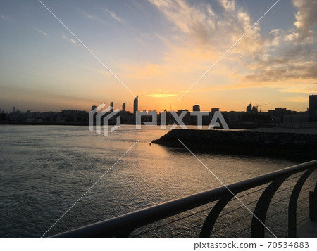 Abu Dhabi: Evening view of the sea, the setting sun, and the buildings in the city Abu Dhabi: Evening view of the sea, the setting sun, and the buildings in the city 70534883