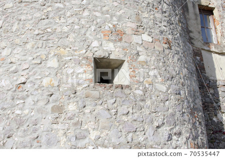 Embrasure, loophole in the wall of an old mountain fortress. Embrasure, loophole in the wall of an old mountain fortress. 70535447