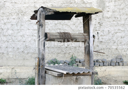 Old well on the background of the wall. Old well on the background of the wall. 70535562