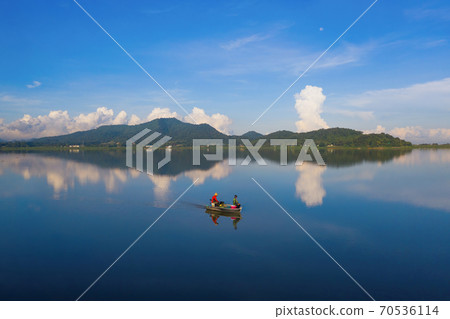 Fisherman on a boat for fishing and catching freshwater fish in nature lake or river with reflection in morning time in Asia in Thailand. People. Fisherman on a boat for fishing and catching freshwater fish in nature lake or river with reflection in morning time in Asia in Thailand. People. 70536114
