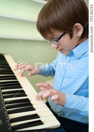 boy with glasses learns to play the synthesizer. boy with glasses learns to play the synthesizer. 70536283