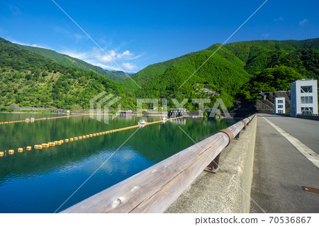 Lake Okutama in summer, the road at the top of the bank, the surface of the lake, and the mountains on the south bank Lake Okutama in summer, the road at the top of the bank, the surface of the lake, and the mountains on the south bank 70536867