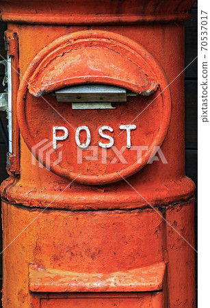 a historic orange letter box. The old red post box pillar close up. The ancient round mailbox. 70537017