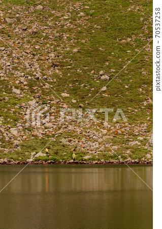 Two boys are standing by the water, two brothers are looking at the lake, the reflection in the water, the alpine lake Brebeneskul. Two boys are standing by the water, two brothers are looking at the lake, the reflection in the water, the alpine lake Brebeneskul. 70537258