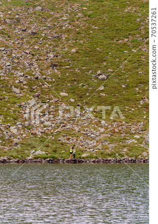 A couple of tourists stand on the edge of a mountain lake, Lake Brebeneskul, the Montenegrin ridge, the Carpathians of Ukraine. A couple of tourists stand on the edge of a mountain lake, Lake Brebeneskul, the Montenegrin ridge, the Carpathians of Ukraine. 70537261