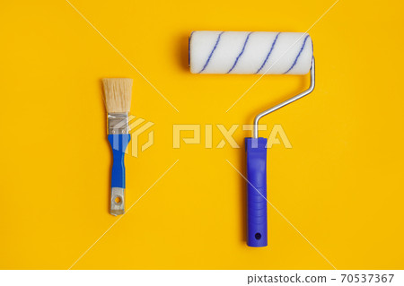 Paint roller and brush isolated on yellow. Painter tools for working with paint. Paint roller and brush isolated on yellow. Painter tools for working with paint. 70537367