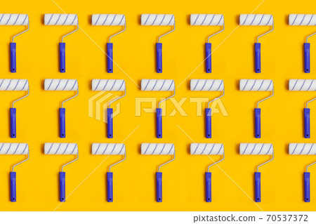 Pattern with paint roller with blue handle on yellow background. Clean roll for painting walls. 70537372