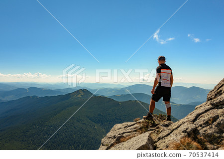 A tourist on top of a large stone block, the top of Smotrych mountain, one of the rocky peaks of the Ukrainian Carpathians. A tourist on top of a large stone block, the top of Smotrych mountain, one of the rocky peaks of the Ukrainian Carpathians. 70537414