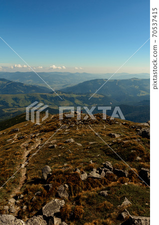 Beautiful landscape with high cliffs and illuminated peaks, blue sky and trails of the Montenegrin ridge, mountain peaks of the Ukrainian Carpathians. Dzembronya village. Beautiful landscape with high cliffs and illuminated peaks, blue sky and trails of the Montenegrin ridge, mountain peaks of the Ukrainian Carpathians. Dzembronya village. 70537415
