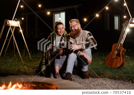 Couple have a good time together on night picnic drinking beverage from bottles Couple have a good time together on night picnic drinking beverage from bottles 70537418