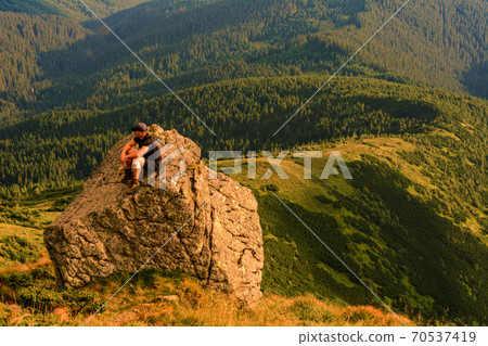 A tourist sits on a rock and looks into the distance, photos on top of Mount Pip Ivan Chornohirsky, landscapes and epic photos of tourists in the mountains. 70537419