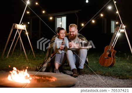 Couple have a good time together on night picnic drinking beverage from bottles Couple have a good time together on night picnic drinking beverage from bottles 70537421