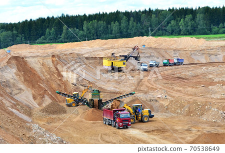 Wheel front-end loader loads sand into a dump truck.  70538649