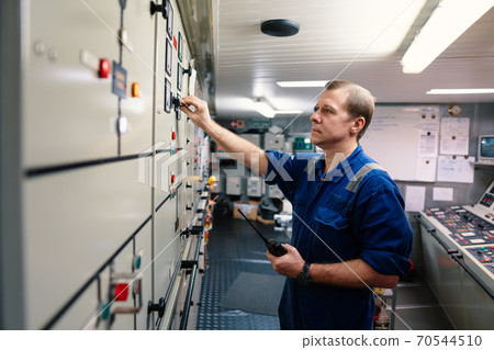 Marine engineer officer controlling vessel engines and propulsion in engine control room Marine engineer officer controlling vessel engines and propulsion in engine control room 70544510