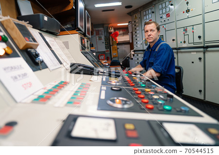 Marine engineer officer controlling vessel engines and propulsion in engine control room 70544515