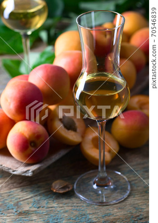 Juicy apricots with leaves and glass of sweet wine . Juicy apricots with leaves and glass of sweet wine . 70546839