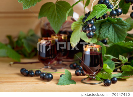 Homemade black currant liqueur and fresh berries . 70547450