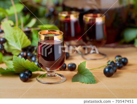Homemade black currant liqueur and fresh berries . 70547451
