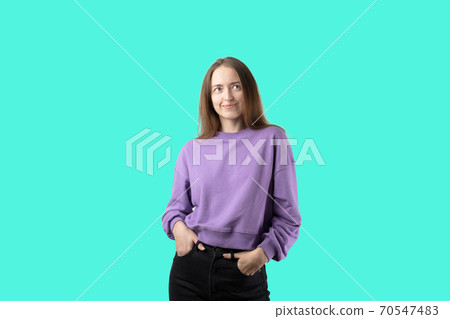 young caucasian woman on turquoise background in purple sweater. Happy millennial girl young caucasian woman on turquoise background in purple sweater. Happy millennial girl 70547483