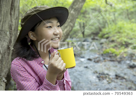 Elementary school trekking image: A girl drinking a drink in front of a stream 70549363
