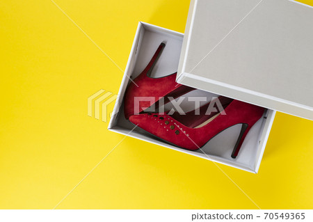 New women's red suede shoes in a box on a yellow background. New women's red suede shoes in a box on a yellow background. 70549365