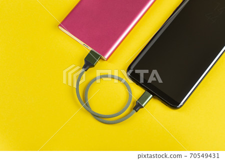 Smartphone Charging with Pink Power Bank on Yellow Background Smartphone Charging with Pink Power Bank on Yellow Background 70549431