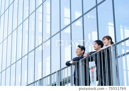 望著大樓前的三個微笑業務人 望著大樓前的三個微笑業務人 70551769