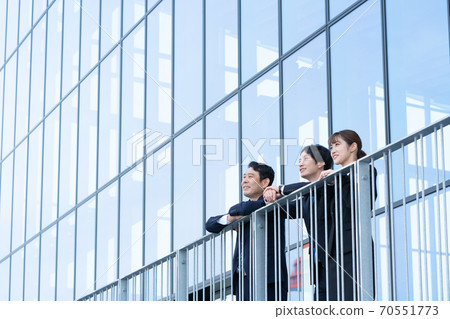 望著大樓前的三個微笑業務人 70551773