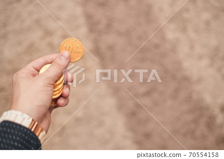 Gold coins in hand on light background 70554158