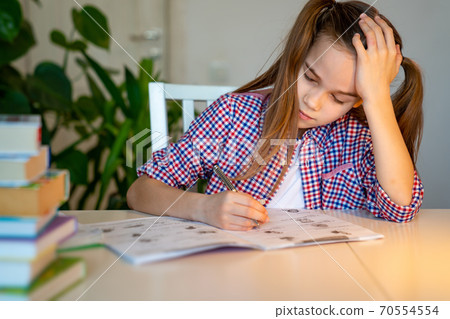 tired schoolgirl asleep doing homework. studying. 70554554