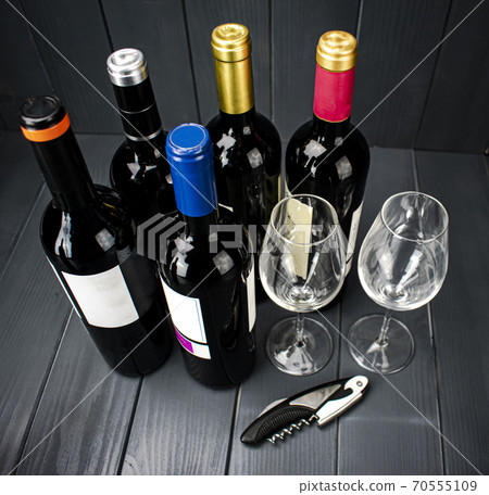red wine bottles with two sparkling wine glasses and a corkscrew for tasting, in gray wooden space red wine bottles with two sparkling wine glasses and a corkscrew for tasting, in gray wooden space 70555109
