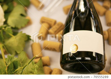 body of a bottle of red wine on white table with corks and green plants on display during a tasting body of a bottle of red wine on white table with corks and green plants on display during a tasting 70555289
