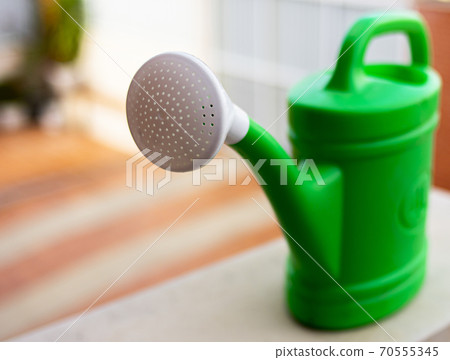 Traditional green watering can with white diffuser to hydrate plants in a private home 70555345