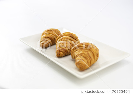 Close-up of three croissants on a plate focused on the center on white background 70555404