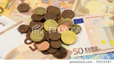 A pile of euro coins on a bed of fifty and twenty euro bills 70555587
