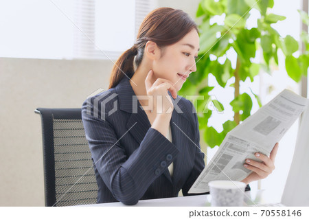 Career woman reading an English newspaper in the office Career woman reading an English newspaper in the office 70558146
