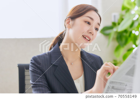 Career woman reading an English newspaper in the office Career woman reading an English newspaper in the office 70558149