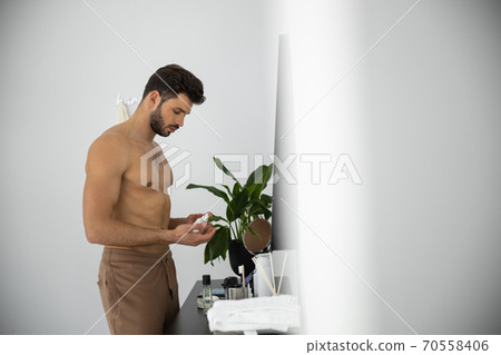 Waist upof man holding jar of facial cream Waist upof man holding jar of facial cream 70558406