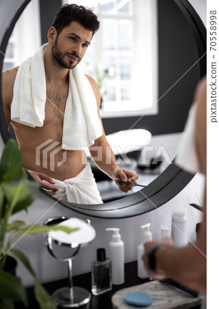 Waist up shot of man looking to himself through the mirror 70558998