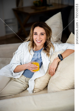 Woman sitting on sofa in living room 70559353