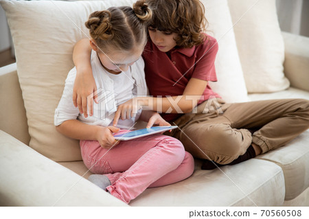 Brother teaching his sister how to use the tablet Brother teaching his sister how to use the tablet 70560508