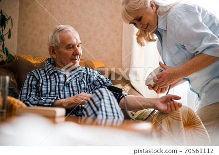 Woman checking husband's blood pressure 70561112