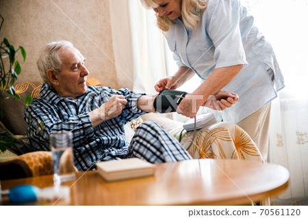 Couple at home measuring blood pressure 70561120