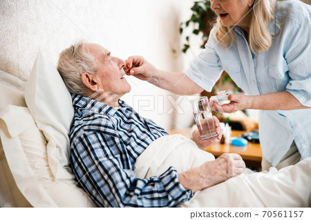 Senior man lying on bed and taking pills Senior man lying on bed and taking pills 70561157