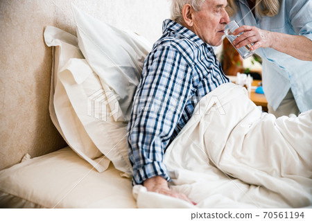 Woman giving drug and drink to her husband Woman giving drug and drink to her husband 70561194
